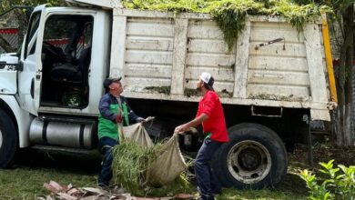 Dos hombres suben basura a un camión de volteo