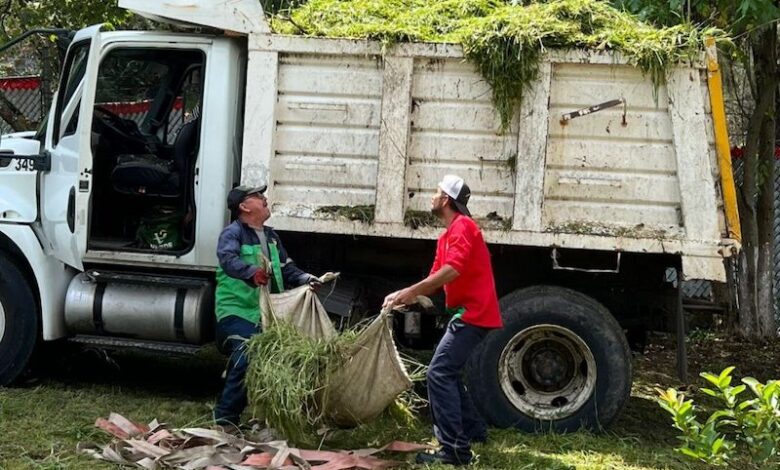 Dos hombres suben basura a un camión de volteo